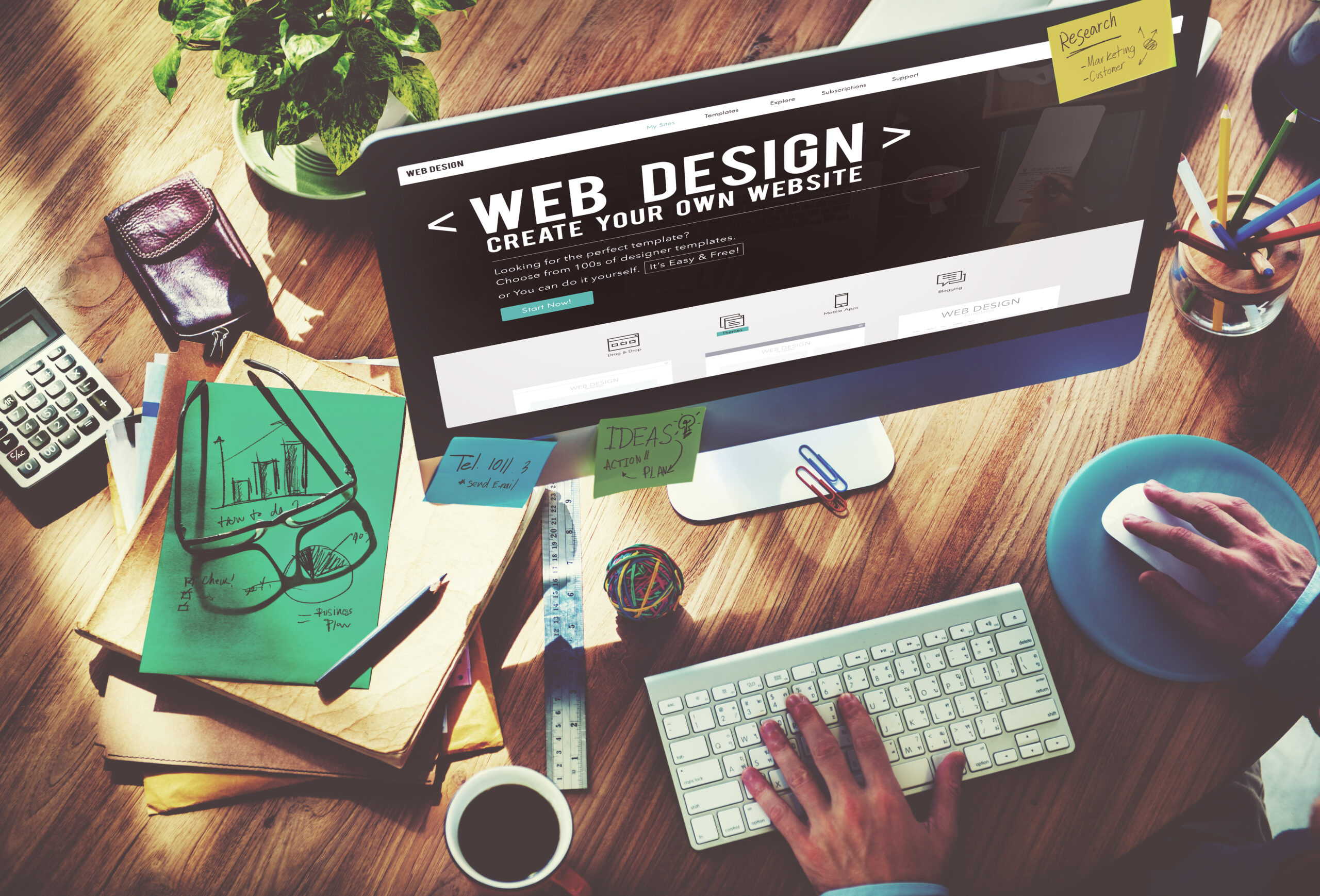 Persona diseñando página web en mesa con gafas, calculadora y material de oficina en Álava