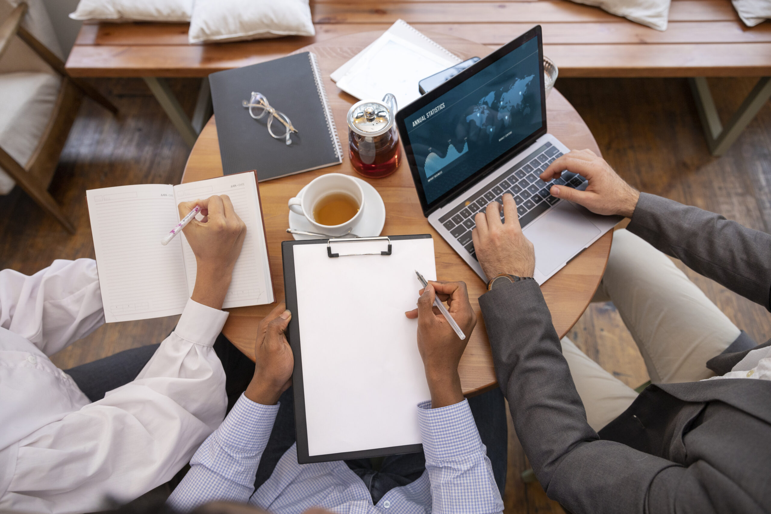 Personas trabajando en equipo en Enova Studios en A Coruña, escribiendo en agenda, cuaderno y portátil