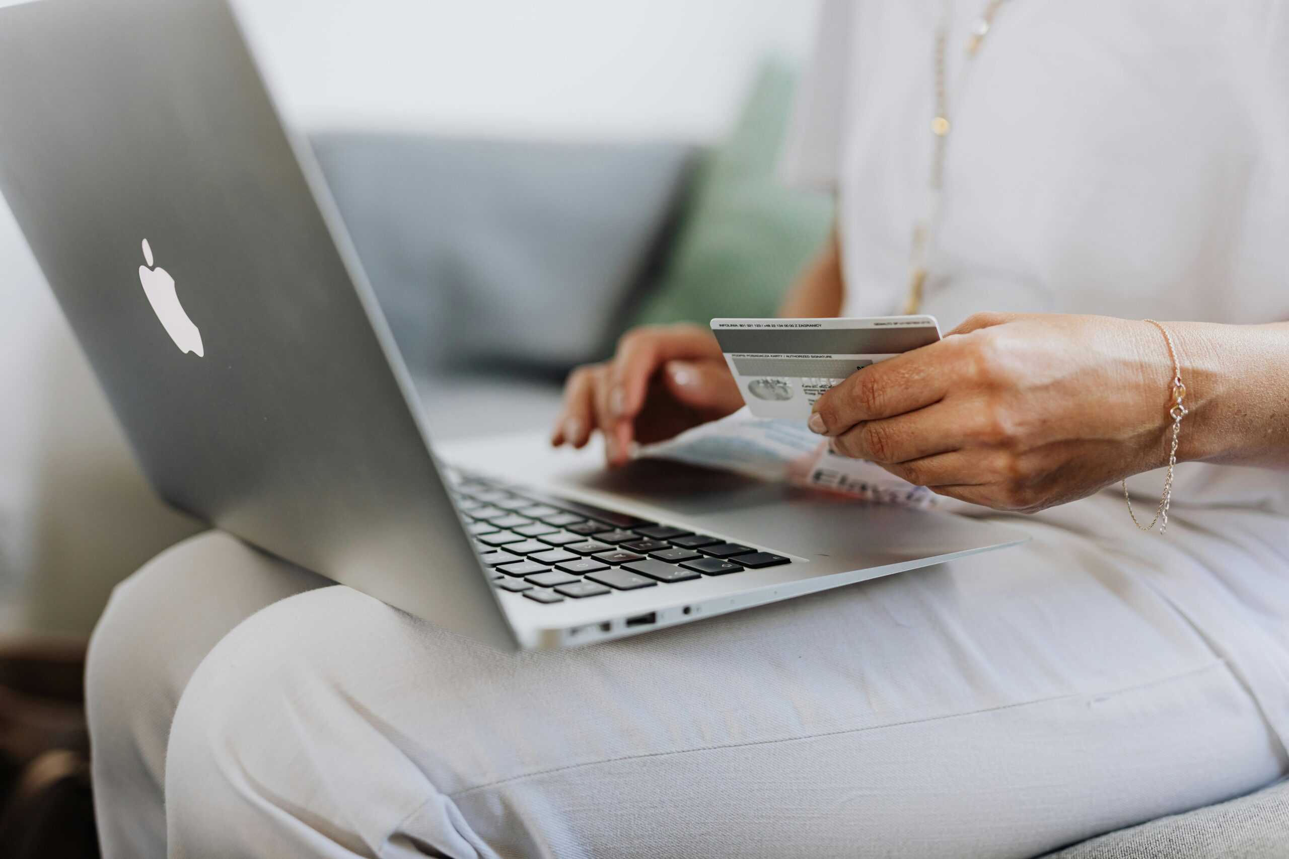 Persona usando un MacBook con tarjeta de crédito para realizar una compra online en un ecommerce en Álava.