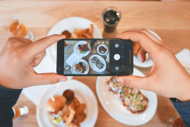 Manos haciendo una foto con el móvil a varios platos en una mesa