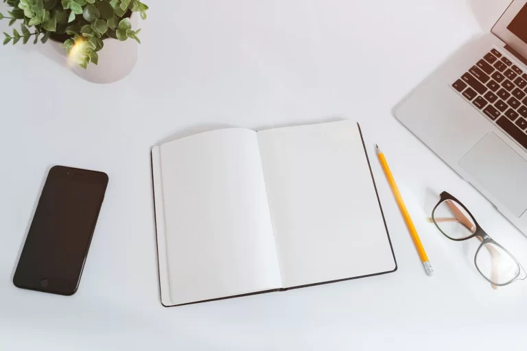 Plan de contenidos para redes sociales: cuaderno abierto, móvil y lápiz sobre la mesa